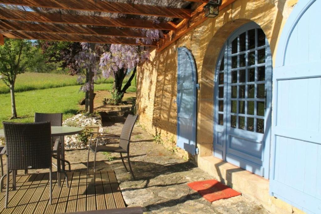 a patio with a table and chairs and a building at Les Combes avec piscine chauffée au nord Sarlat in LʼAir