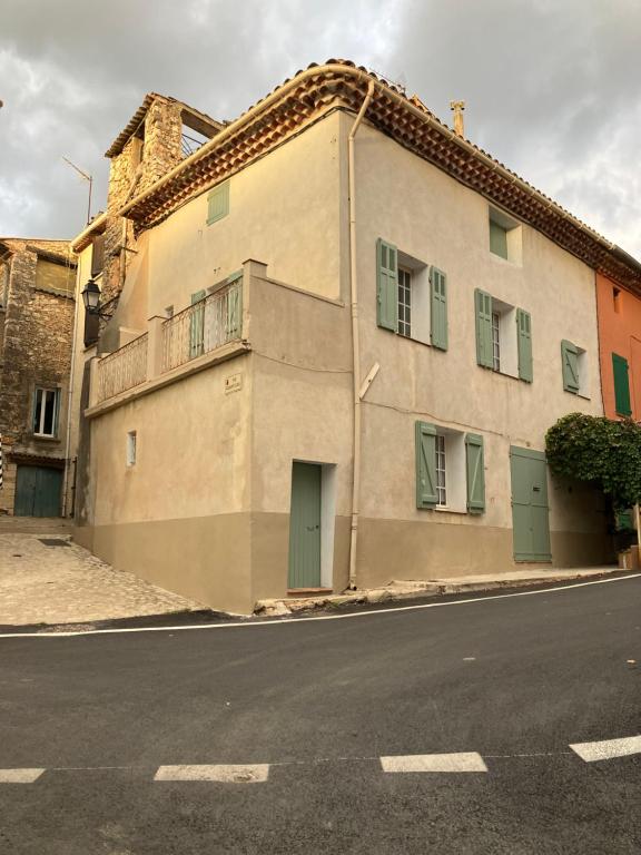 a building with green doors on the side of a street at Maison de village in Pontevès