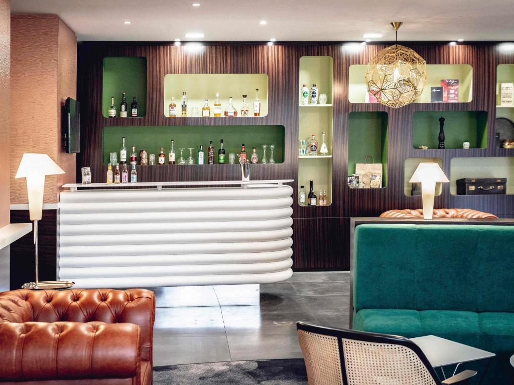 a bar with a couch and a chair in a room at Mercure Belfort Centre in Belfort