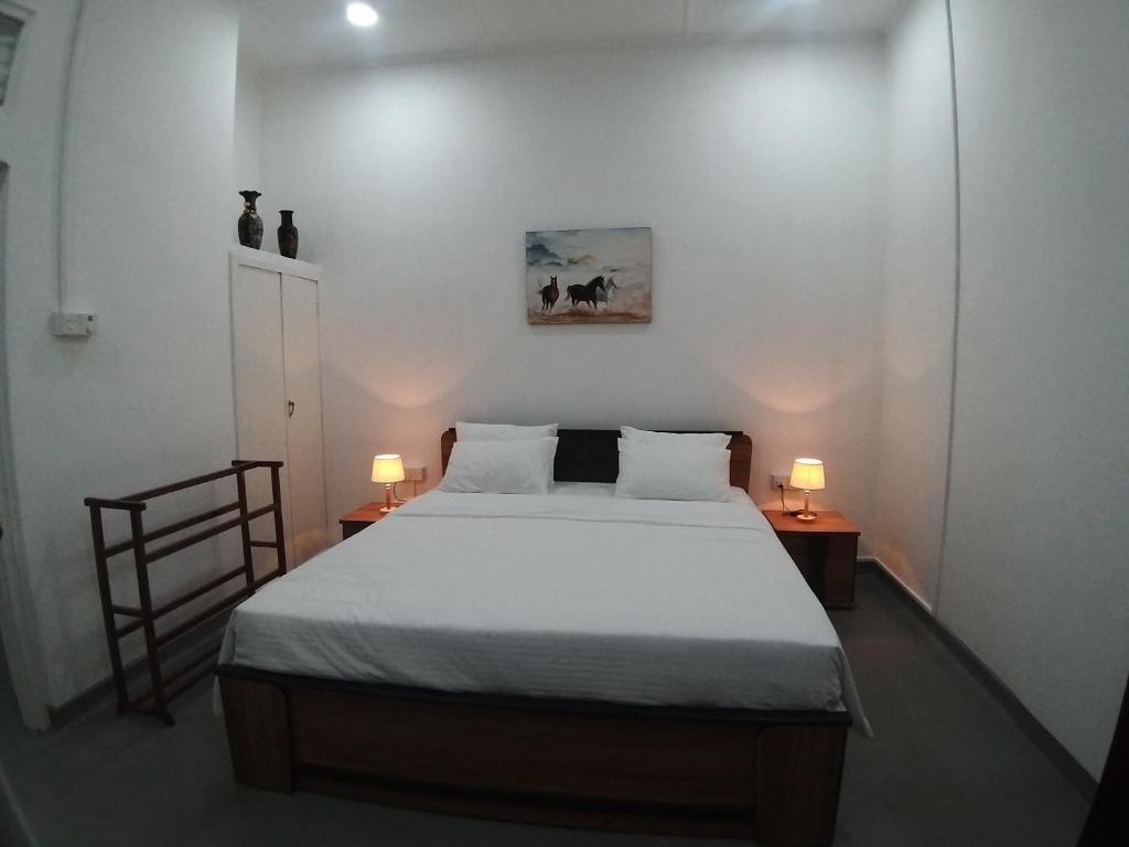 a bedroom with a bed and two lamps on two tables at White Room in Colombo Seven in Colombo
