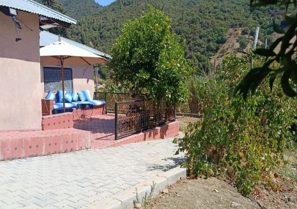 a patio with blue chairs and an umbrella at Ferme Panorama in Ouazzane