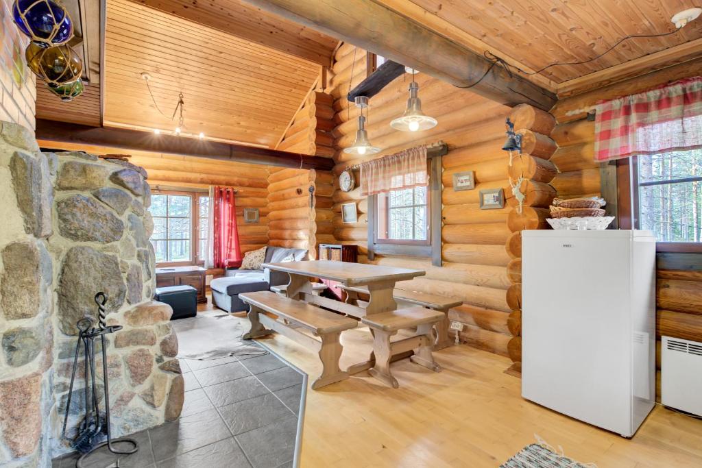 a dining room in a log cabin with a table and a refrigerator at Laavu 13 Original Log Cabin with Sauna in Pyhätunturi