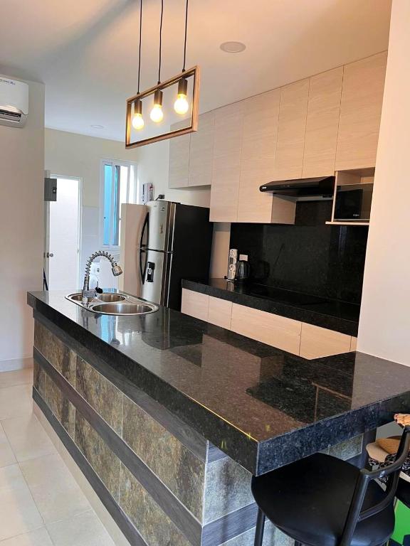 Una cocina con encimera negra y refrigerador. en Departamento playa via Data paraiso, en Playas
