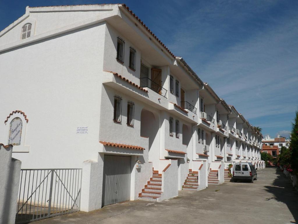 un bâtiment blanc avec une voiture garée à côté dans l'établissement Inocencia, à Alcossebre