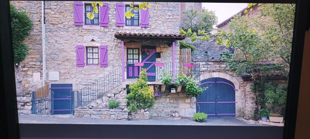 an old stone house with purple doors and windows at CARDABELLE maison authentique à louer in Millau