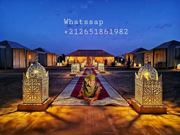un jeune enfant est assis sur un tapis dans une cour dans l'établissement Sahara Relax Camp, à Merzouga