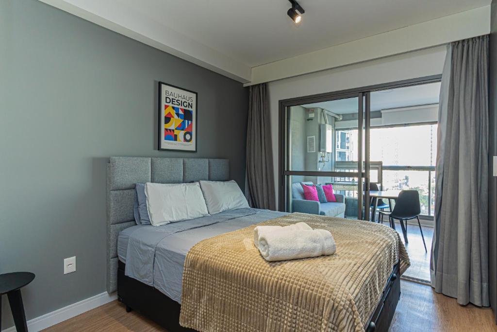 a bedroom with a bed and a room with a balcony at Bauhaus Vista 360° - Piscina Rooftop in Sao Paulo