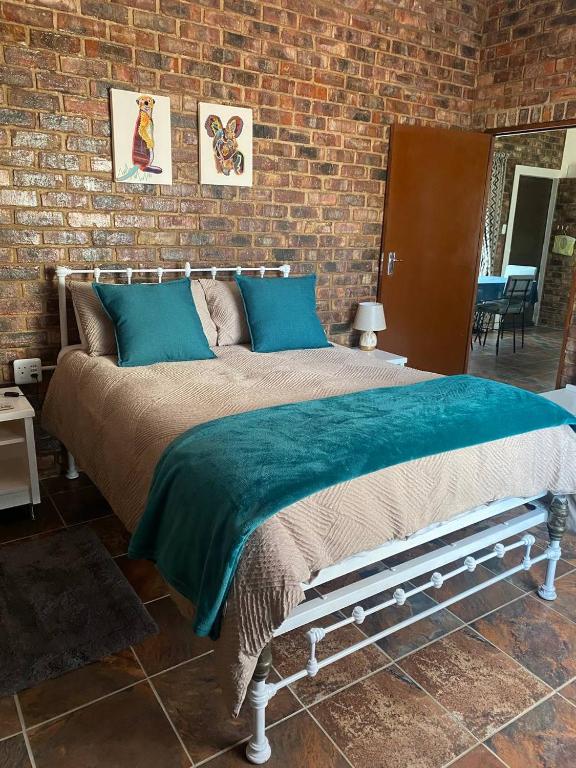 a bedroom with a bed with a brick wall at Come Again Self Catering in George