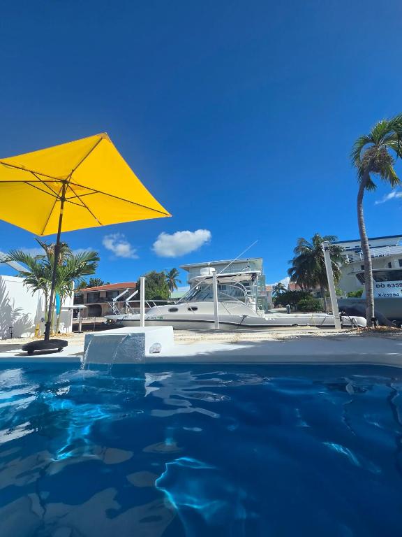 a swimming pool with a yellow umbrella and palm trees at Direct access Canal front with Pool 2 bed 2 bath in Marathon