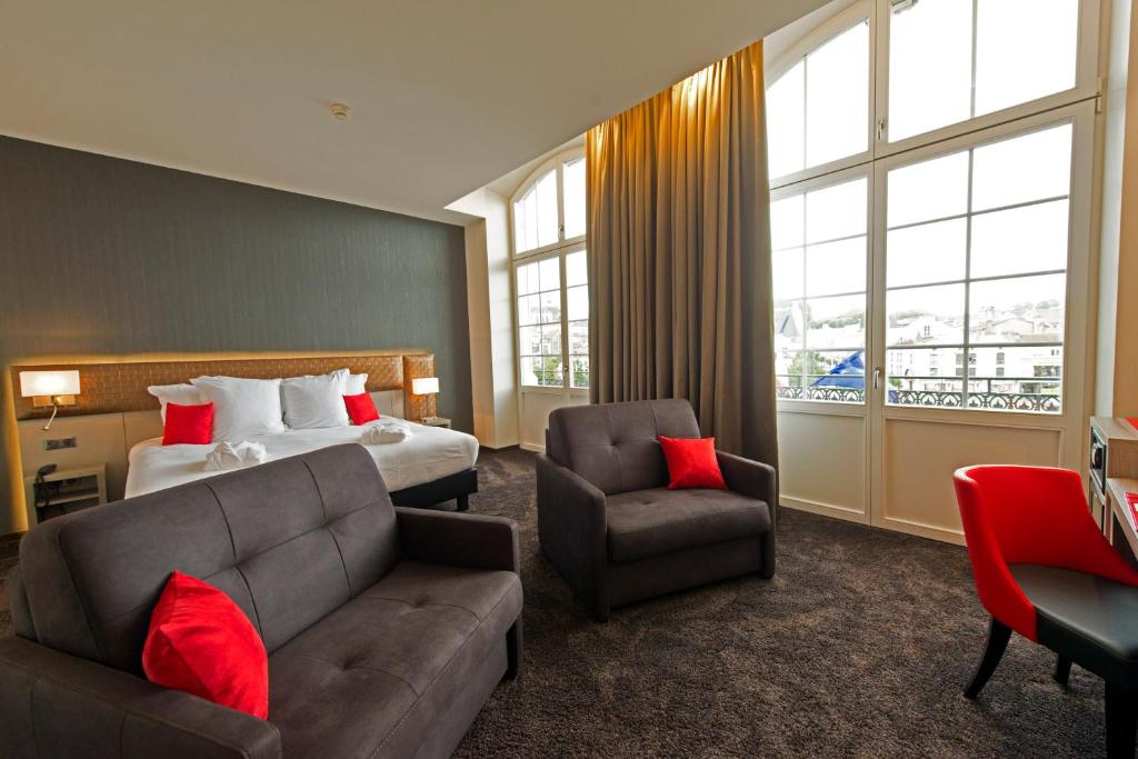 um quarto de hotel com uma cama, um sofá e uma cadeira em Les Jardins du Mess em Verdun-sur-Meuse