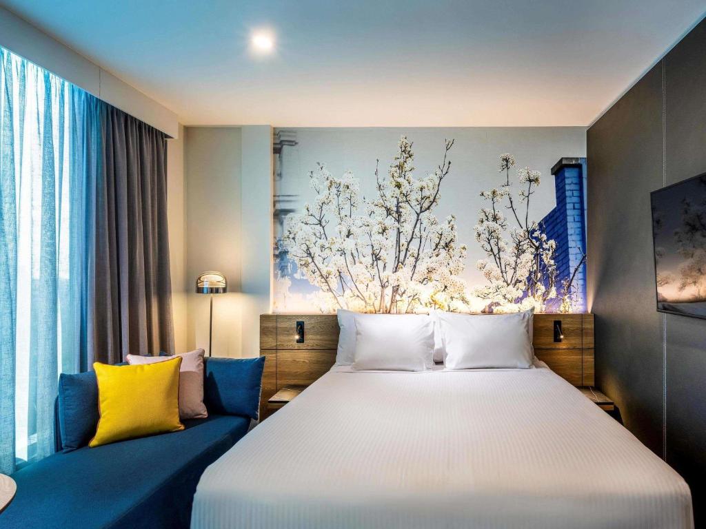a bedroom with a large white bed and blue couch at Novotel Melbourne Preston in Melbourne