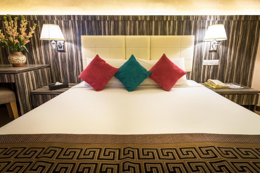 a bedroom with a large bed with red and green pillows at Hotel Sentral Melaka @ City Centre in Melaka
