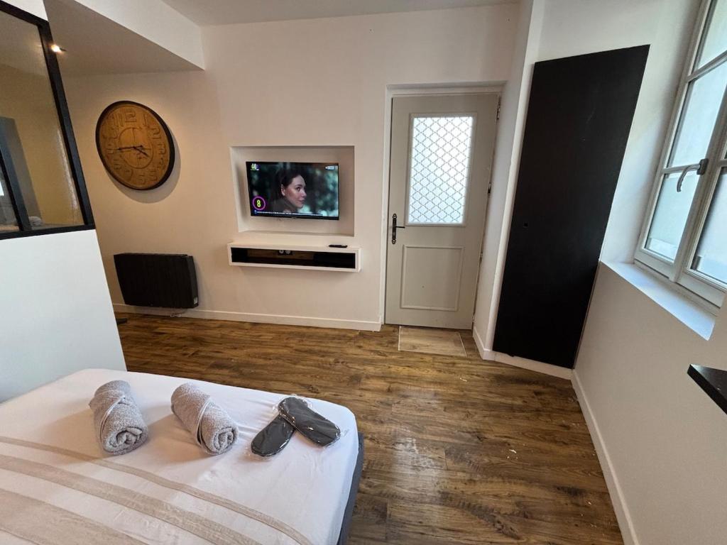 Una habitación con una cama con pantuflas y un televisor. en A l'angle du vieux marché, en Niort
