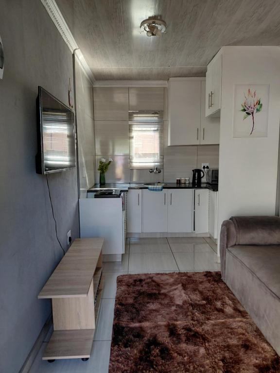 a small kitchen with white cabinets and a couch at Mama R's Budget-friendly BACKROOM 2 in Newcastle