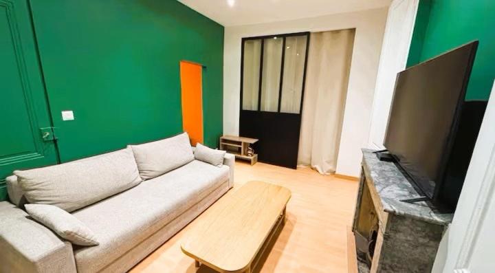 a living room with a couch and a green wall at Appartement proche des transports in Villeurbanne
