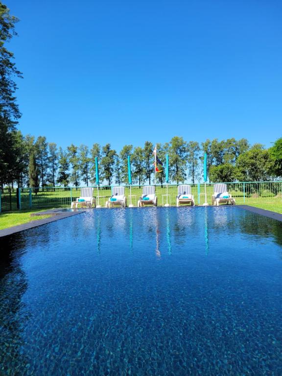 una piscina de agua azul con sillas en un parque en La Perdida Casa de Campo, en San Antonio de Areco