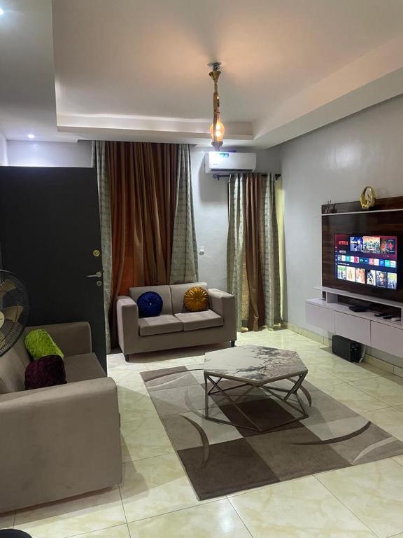 a living room with couches and a flat screen tv at Abiluxe in Hausa