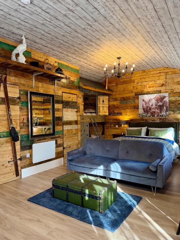 Hotel Willow Court Farm-Studio North & Petting Farm, 8 mins from Legoland & Windsor, 15 mins from Lapland UK, a living room with a blue couch and wooden walls at Willow Court Farm-Studio North & Petting Farm, 8 mins from Legoland & Windsor, 15 mins from Lapland UK in Windsor