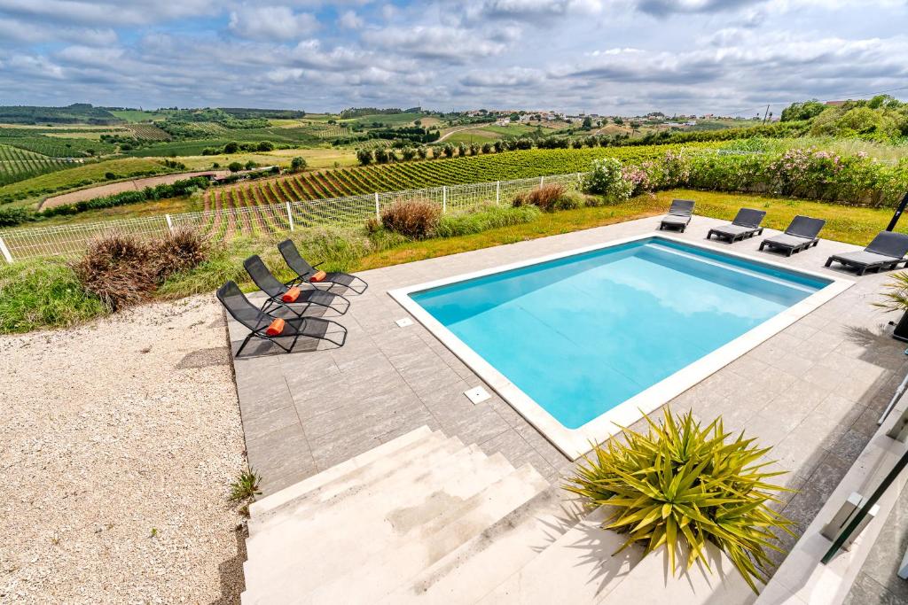 an image of a swimming pool in a yard with chairs at Villa Adão Lobo in Adão Lobo