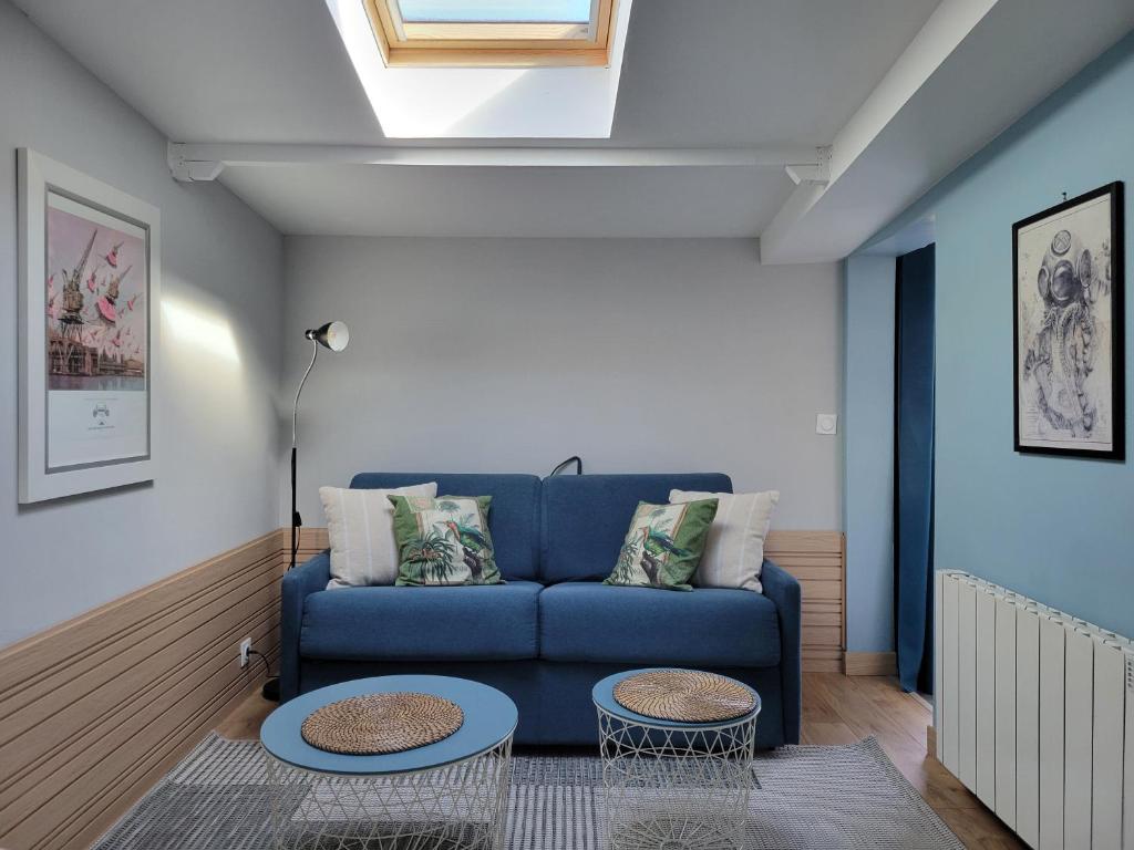 a living room with a blue couch and two tables at T1 rez de jardin proche mer in Plérin