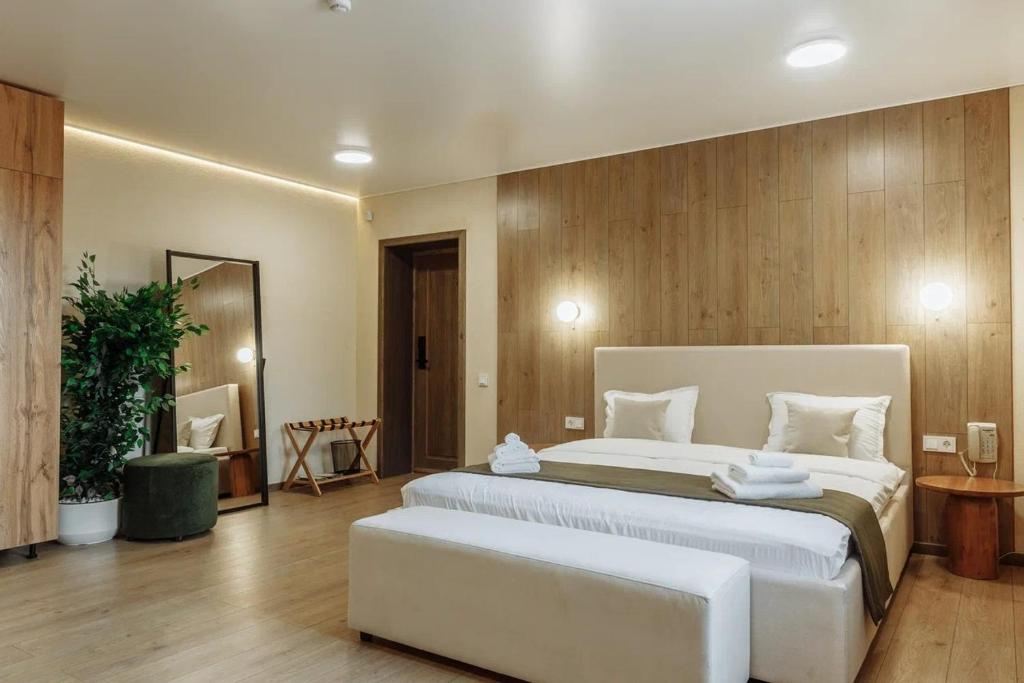 a large bedroom with a large white bed with a bench at Avenue Boutique Hotel in Borovoye