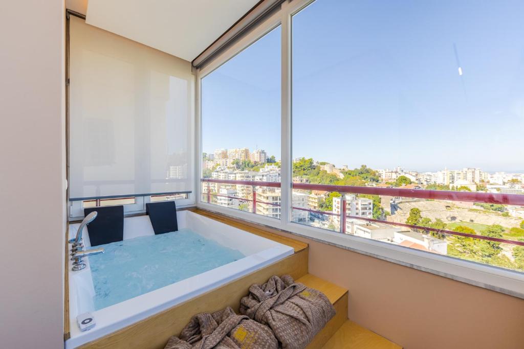 a bathroom with a tub and a large window at Marina Luxury Jacuzzi Suites by PS in Durrës