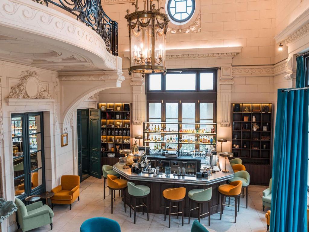 a bar in a room with chairs and a chandelier at Hotel Novotel Domaine de Maffliers - Paris Val-d'Oise in Maffliers