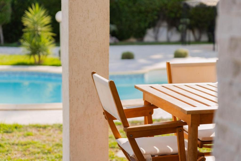 a wooden table and chairs next to a pool at Villa Oliviera in Akouda