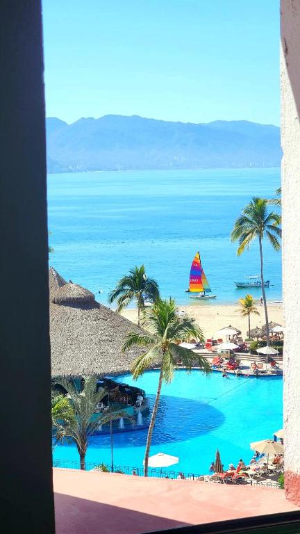a view of a beach with a boat in the water at Ocean View 2BR Apt at Resort, 1 Block to the Beach in Puerto Vallarta