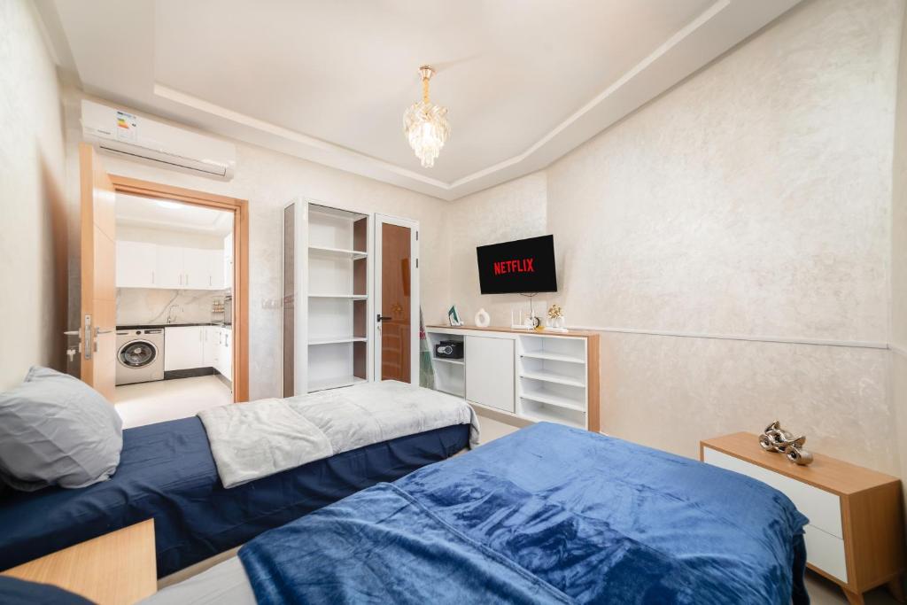 a bedroom with two beds and a tv on the wall at Jaws Wave ESSAOUIRA in Al Ghar