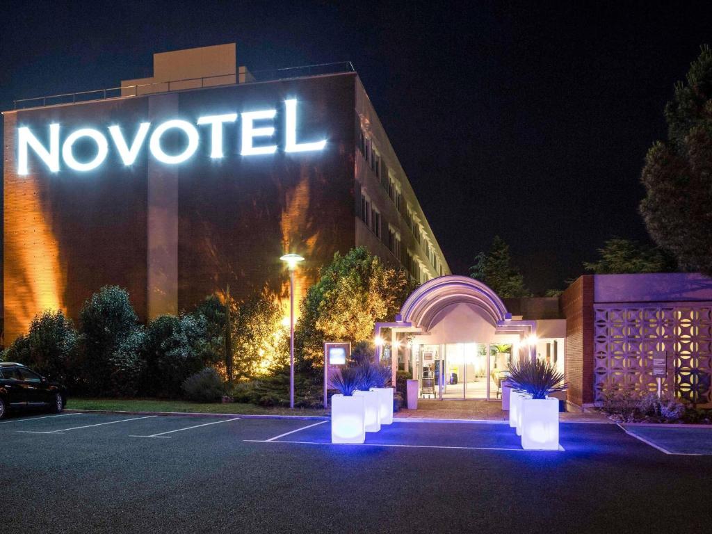 a hotel with a sign on the side of it at night at Novotel Toulouse Purpan Aéroport in Toulouse