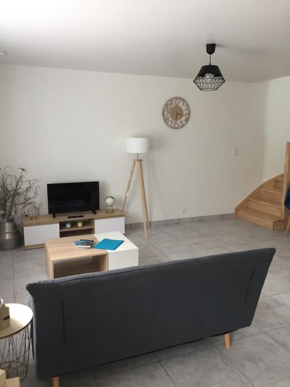 a living room with a couch and a clock on the wall at Appartement avec jacuzzi privatif in Moustoir-Ac