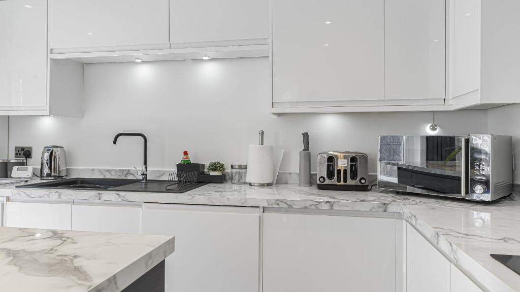 a white kitchen with white cabinets and a microwave at Highland House in Birmingham