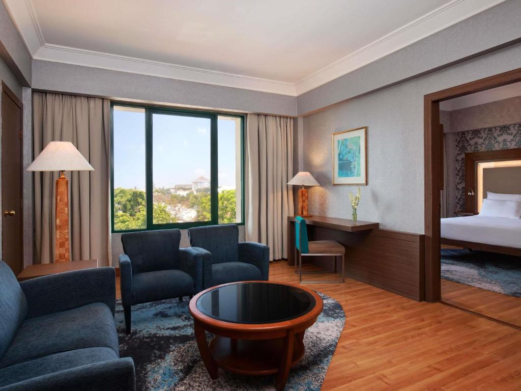 a hotel room with a bed and a living room at Novotel Solo in Solo