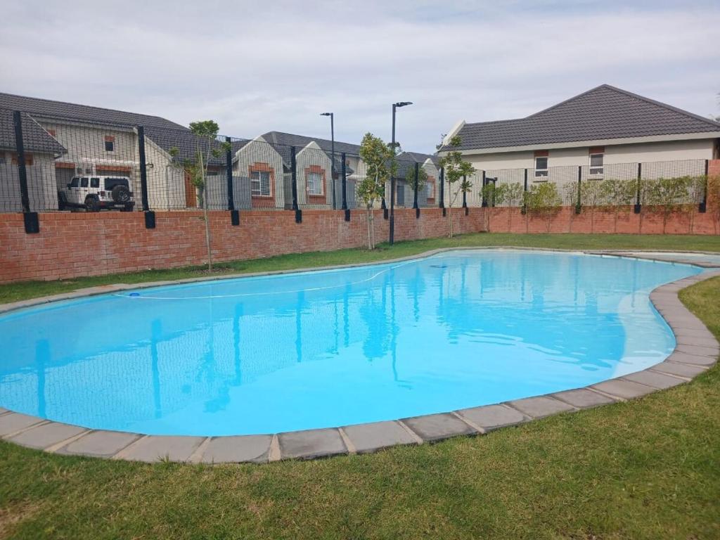 a large blue swimming pool in a yard with houses at Unit 48 1onYork in George