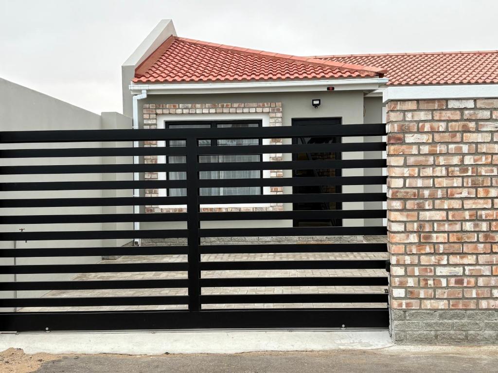 a black fence in front of a house at Comfy Cottage in Walvis Bay