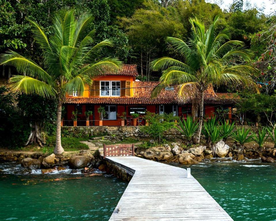 a house with palm trees and a bridge over a river at CASA DA ILHA INN AND SPA Anexo1 in Angra dos Reis