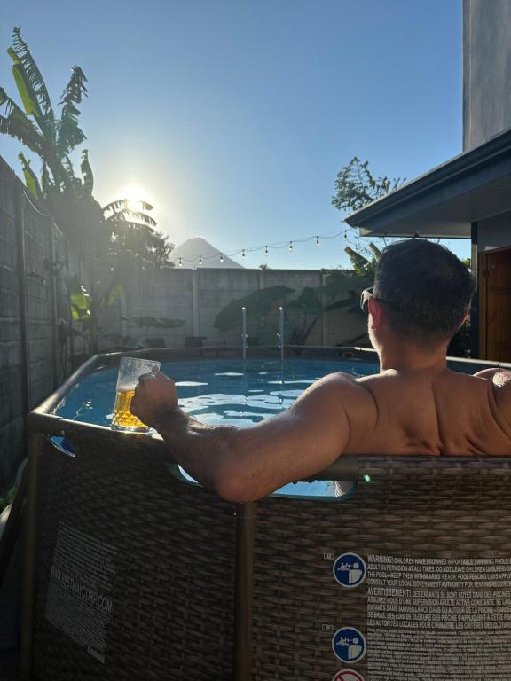 a man in a hot tub with a drink at Brisas del Volcán BnB in Fortuna