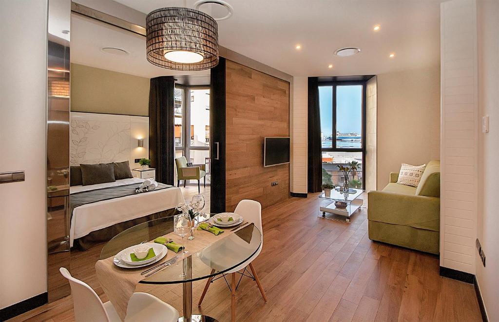 uma sala de estar com uma cama, uma mesa e cadeiras em Apartamentos Suites Oficentro Deluxe em Málaga