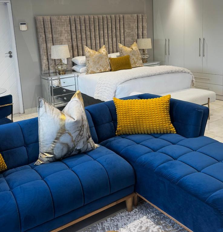 a living room with a blue couch and a bed at Luu Luxury Suite in East London