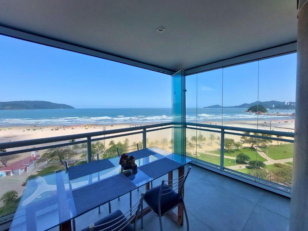 a room with a table and chairs and a view of the beach at Book Santos - Unlimited 901 - Frente Mar com Vista Panorâmica in Santos