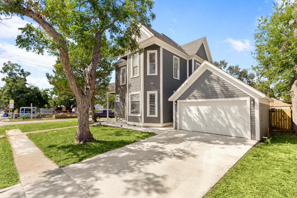 a house with a garage and a tree at The Bowie Grand - Historic Comfort in Seguin in Seguin