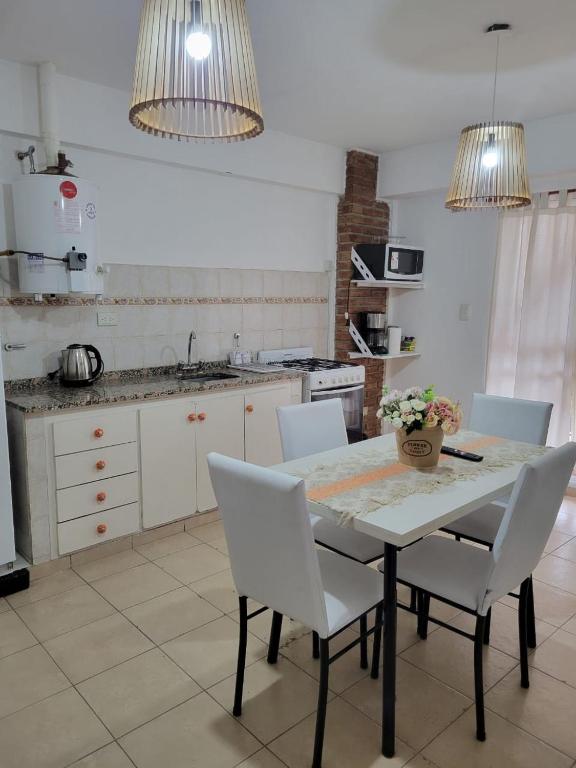 a kitchen with a table with white chairs and a counter at Departamento Urquiza2 in Alta Gracia