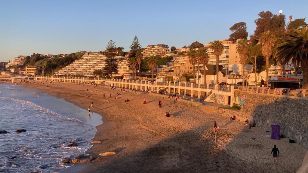 a group of people on a beach next to the ocean at casa vista pacifico in Concón