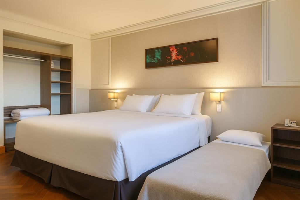 Dos camas en una habitación de hotel con sábanas blancas. en Suite Confort - Resort em Gramado, en Gramado