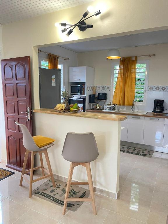 a kitchen with a counter and two stools in it at Soleil éclatant in Sainte-Anne