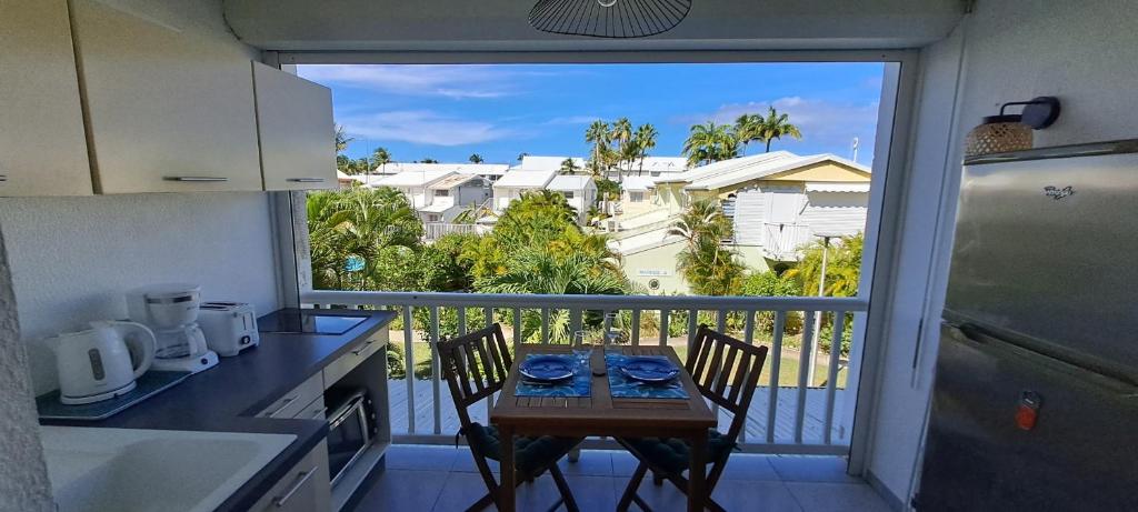 a kitchen with a table and a balcony with a view at Evasion Tropicale in Saint-François