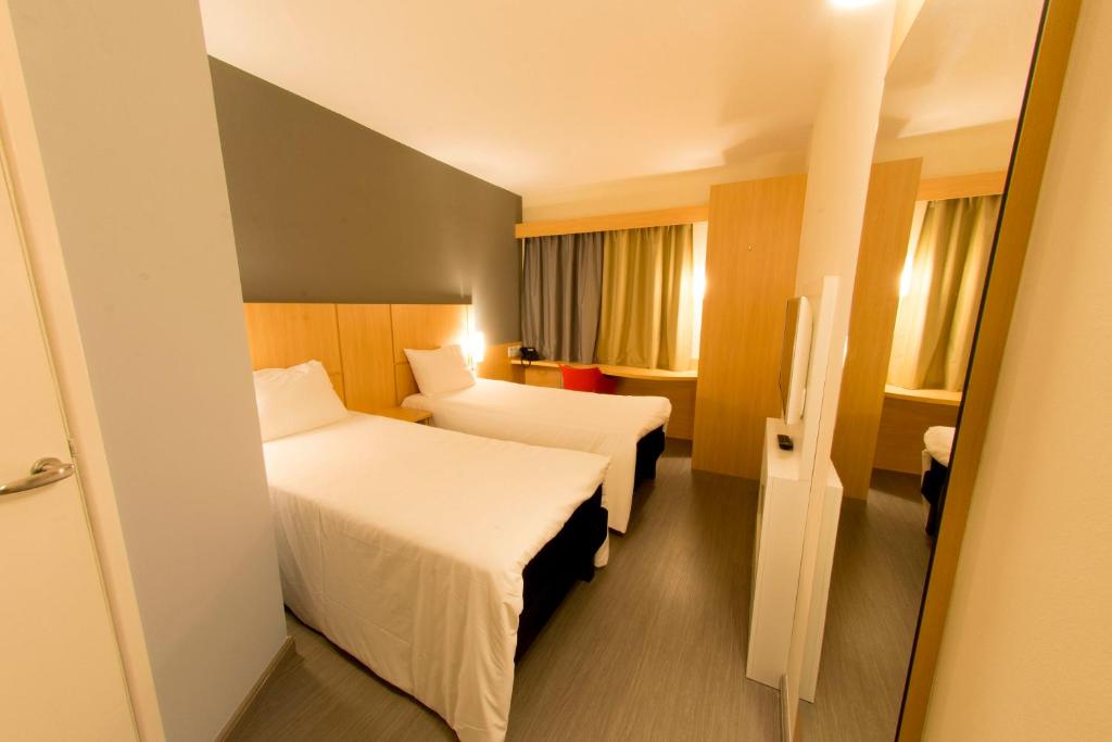 a hotel room with two beds and a window at Transamerica Fit Aracruz in Aracruz