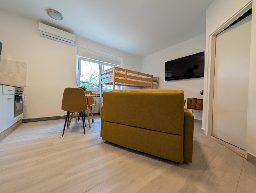 a living room with a yellow couch and a kitchen at Cozy Studio in Sesvete in Sesvete