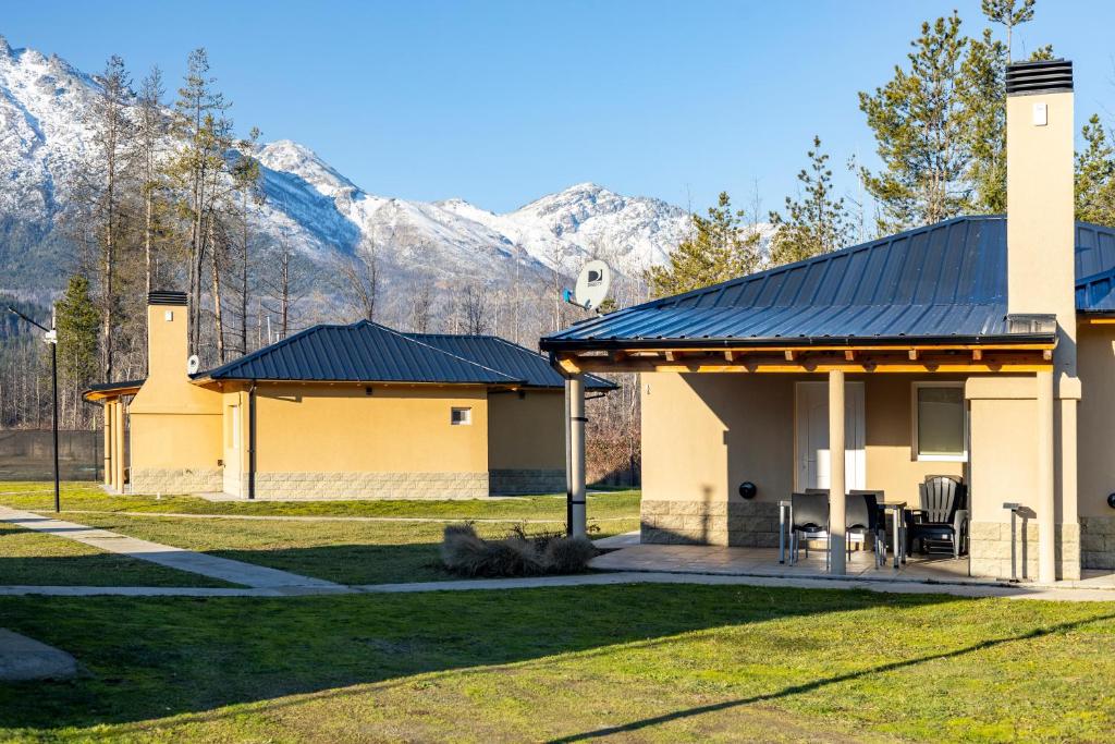 une maison avec un toit et des montagnes en arrière-plan dans l'établissement Complejo Turistico Paralelo 42, à Lago Puelo